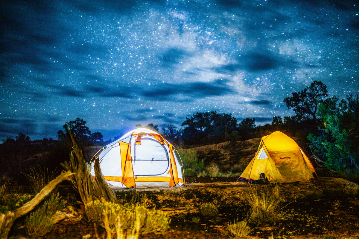 Illuminated camping tents beneath the Milky Way in Canyonlands National Park on a clear desert night.