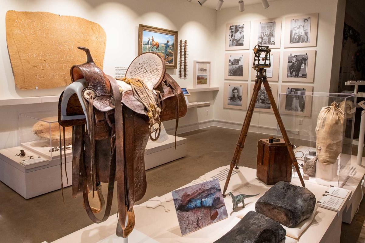 Western saddle and historic camera equipment displayed inside the Moab Museum as part of an exhibit on the region's history and culture.