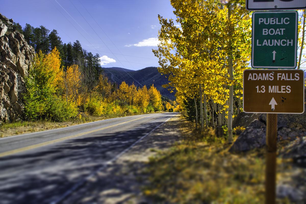 Fall road lined with changing aspens, leading to the East Inlet trailhead