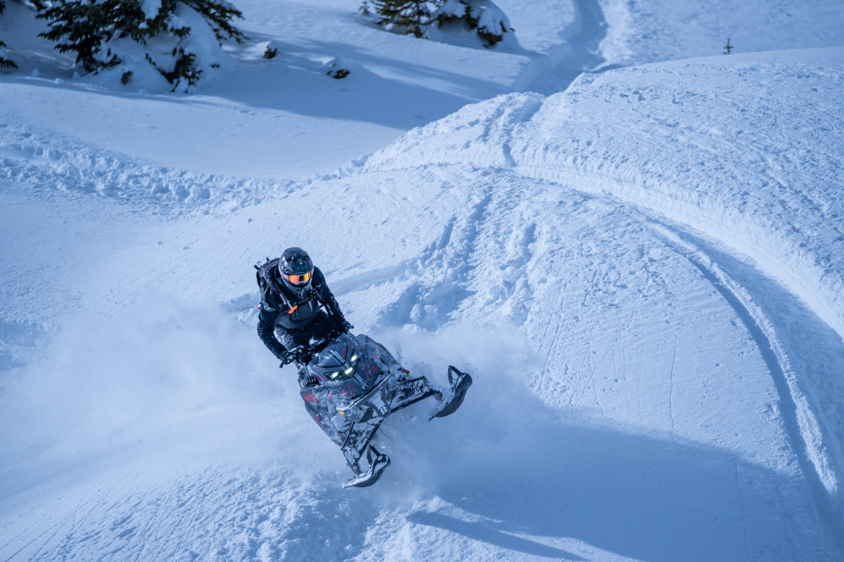 Snowmobile going over a hill in deep snow