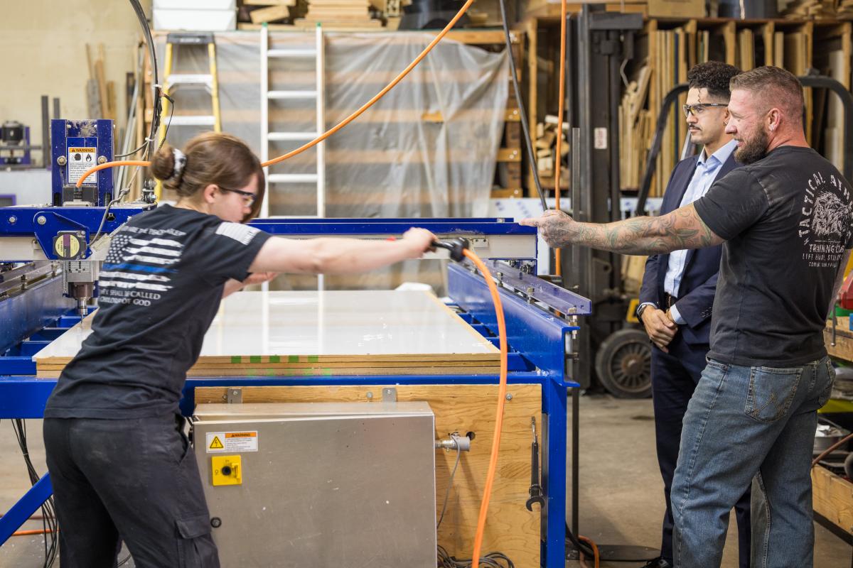 This image depicts workers at C&E Creative, a local Greeley business. A woman and two men are working in an industrial building.