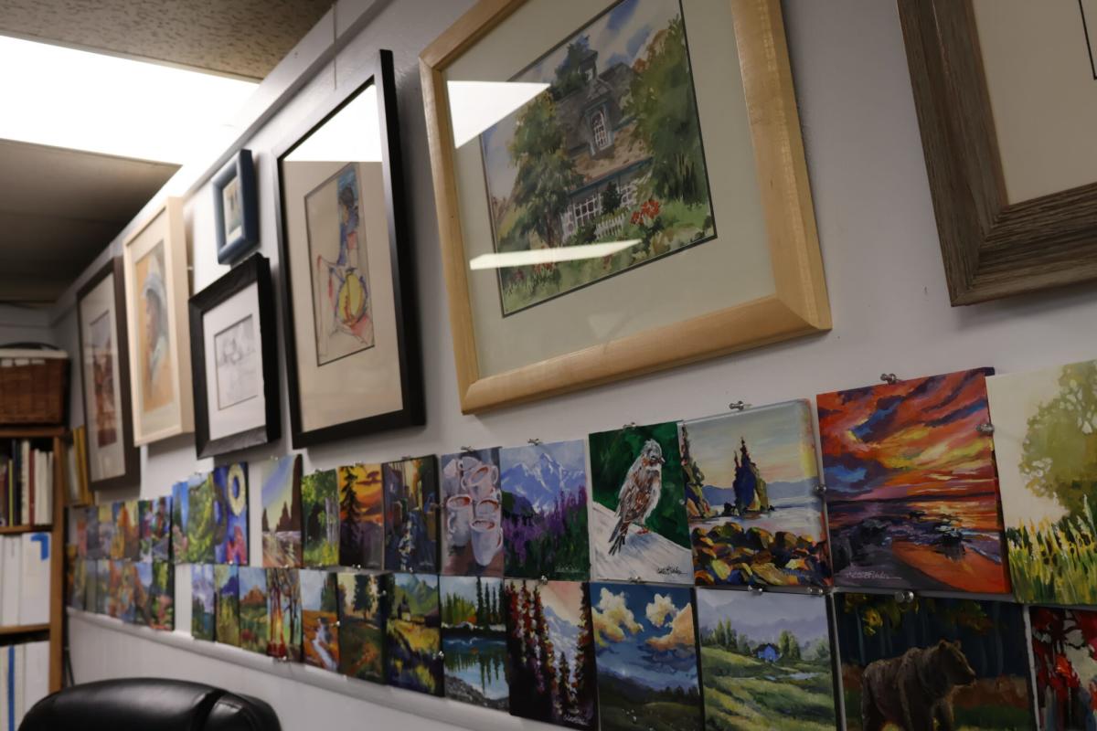 A gallery wall covered in colorful acrylic paintings and framed art in Greeley, Colorado