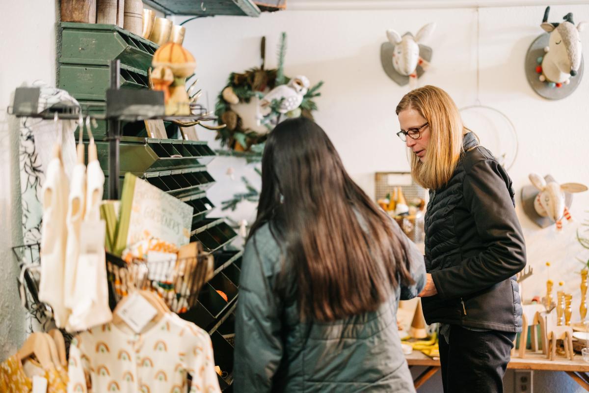 Two women shopping in a boutique, one with her back facing the camera