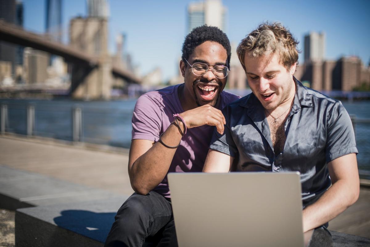 Two men sitting on floor using MacBook