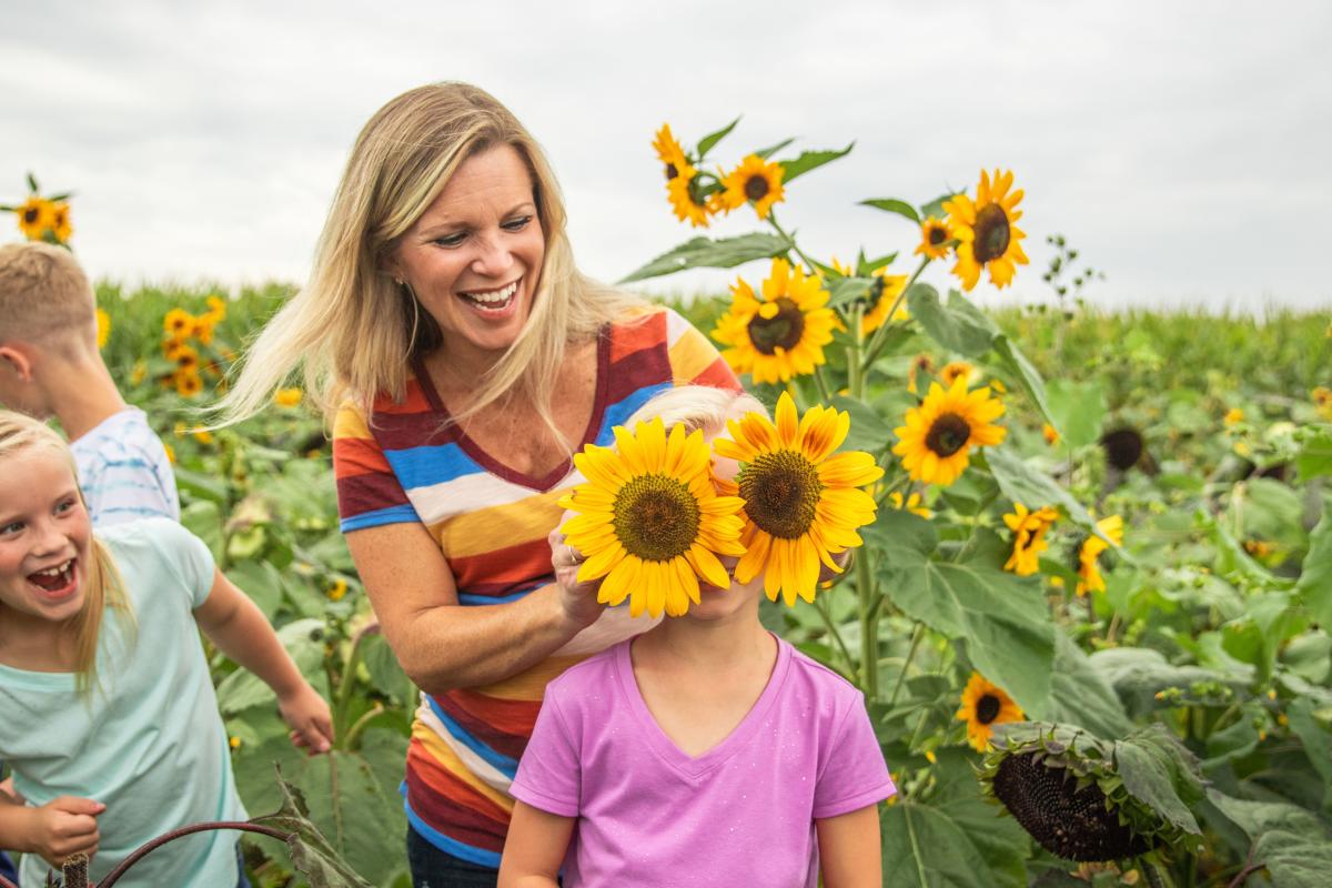 Mother holding sunflowers over daugthers eyes during a photo