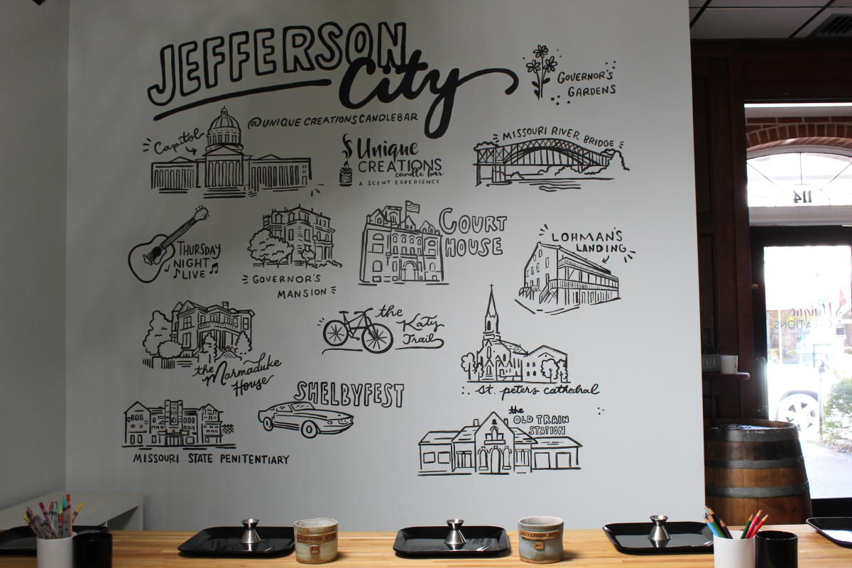 three candle creation stations set up in front of Jefferson City mural