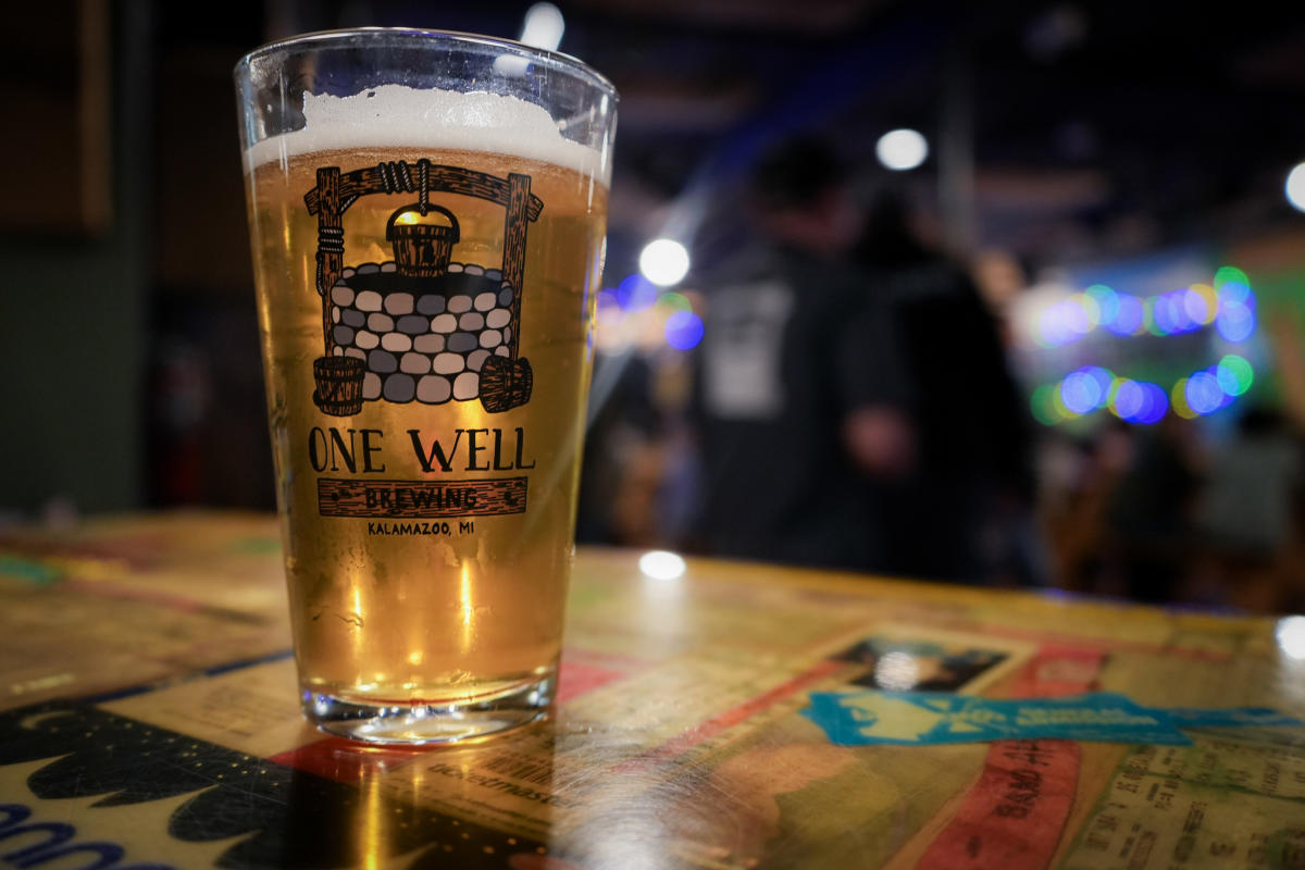 A glass of One Well Brewing company beer sits on a table at their brewery.
