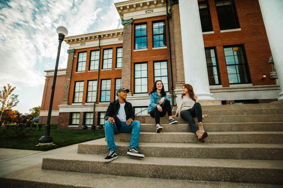 People sitting on the steps of a university building