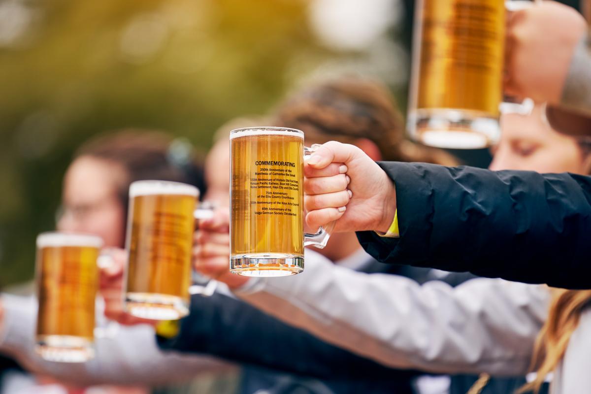 a group of hands holding out mugs of beer