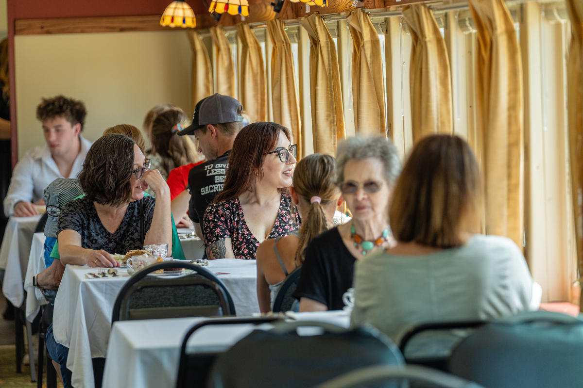 women sitting at tables, some are chatting others are looking out a window