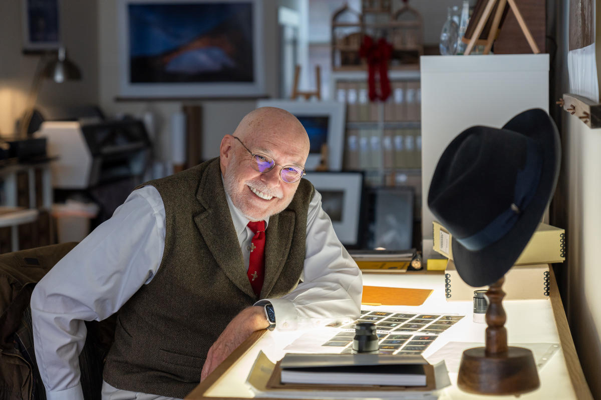 a man smiles at the camera, he's in photography studio