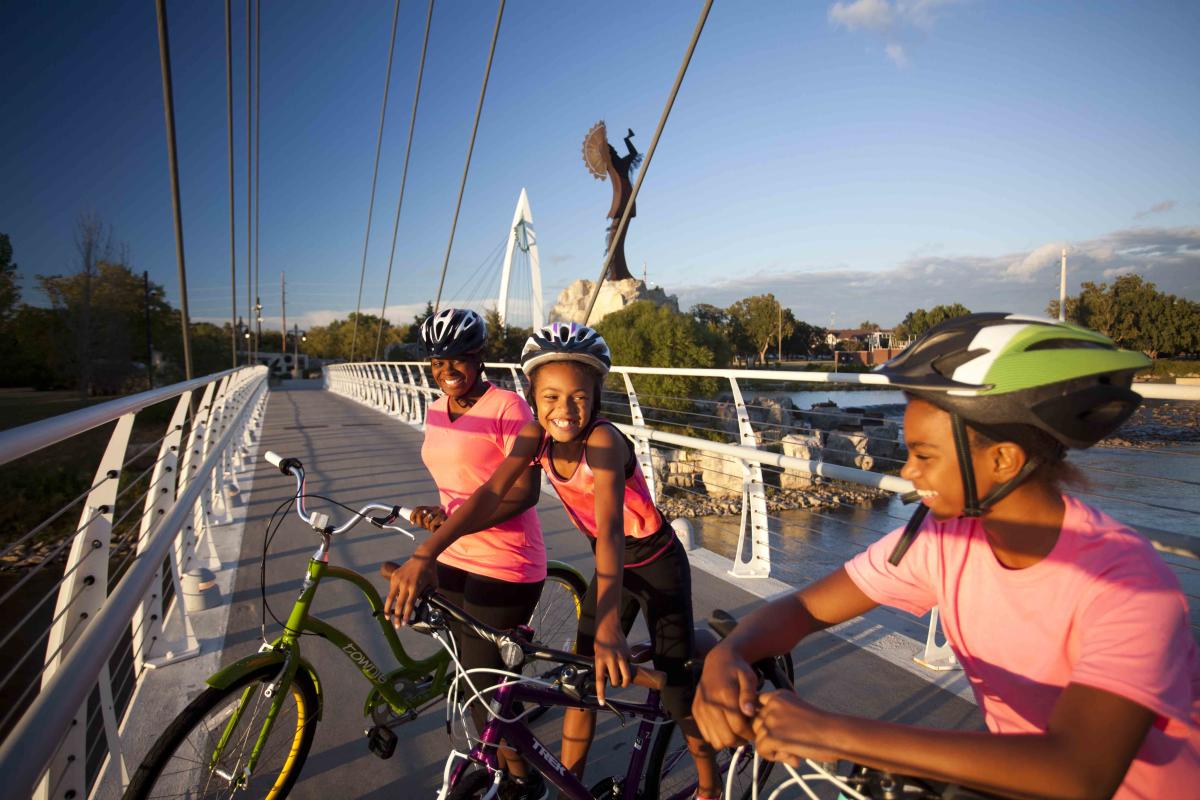 Cyclists pose at the Keeper of the Plains on the Arkansas River