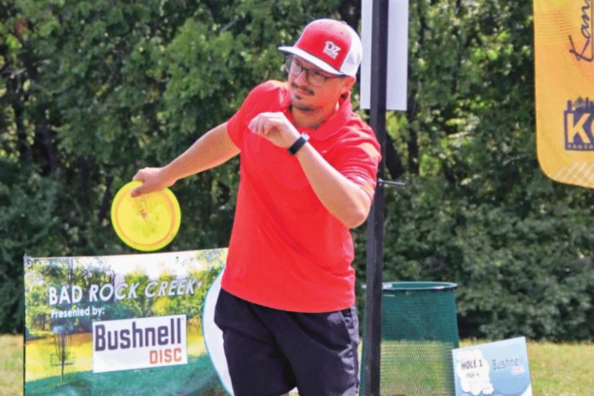 man throws a yellow disc golf disc