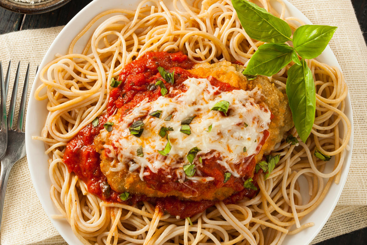 cheese and sauce covered breaded chicken breast on a bed of spaghetti