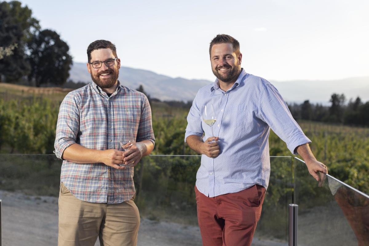 David Paterson and Felix Egerer of Tantalus Vineyards stand outside the vineyard holding glasses of wine