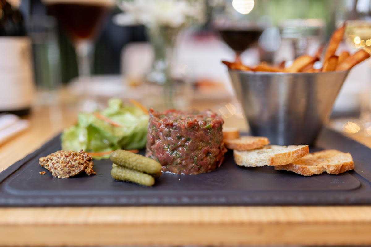 Steak tartare plated with cornichons, mustard, and toasted baguette at Bouchons Bistro in downtown Kelowna