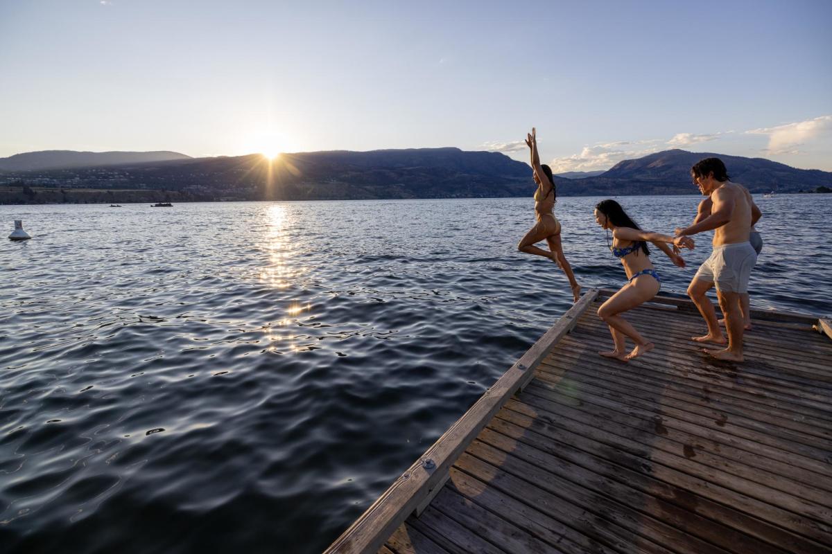 Friends jumping off the dock into Okanagan Lake at sunset in City Park
