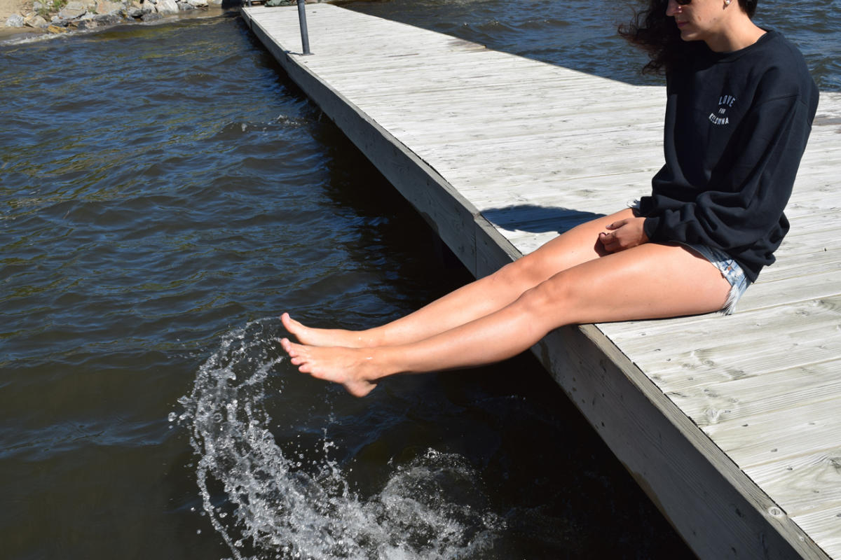 A Woman Putting Her Feet Into A Lake