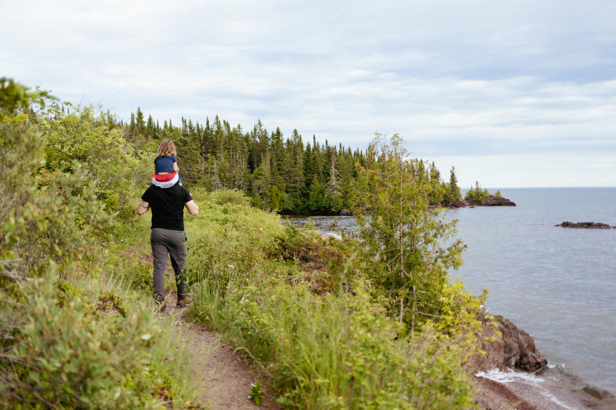 Daughter on dad's shoulders while hiking Lake Superior Shorelines