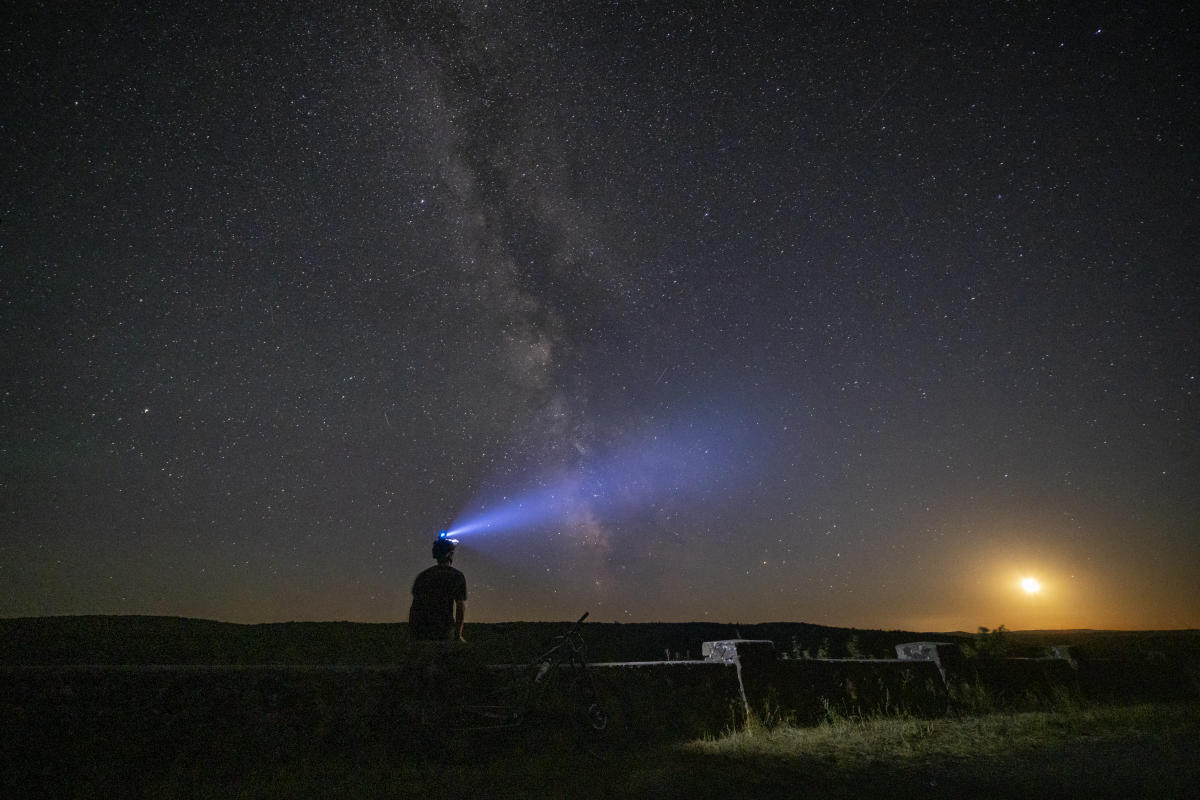 Person with headlamp looking into dark sky
