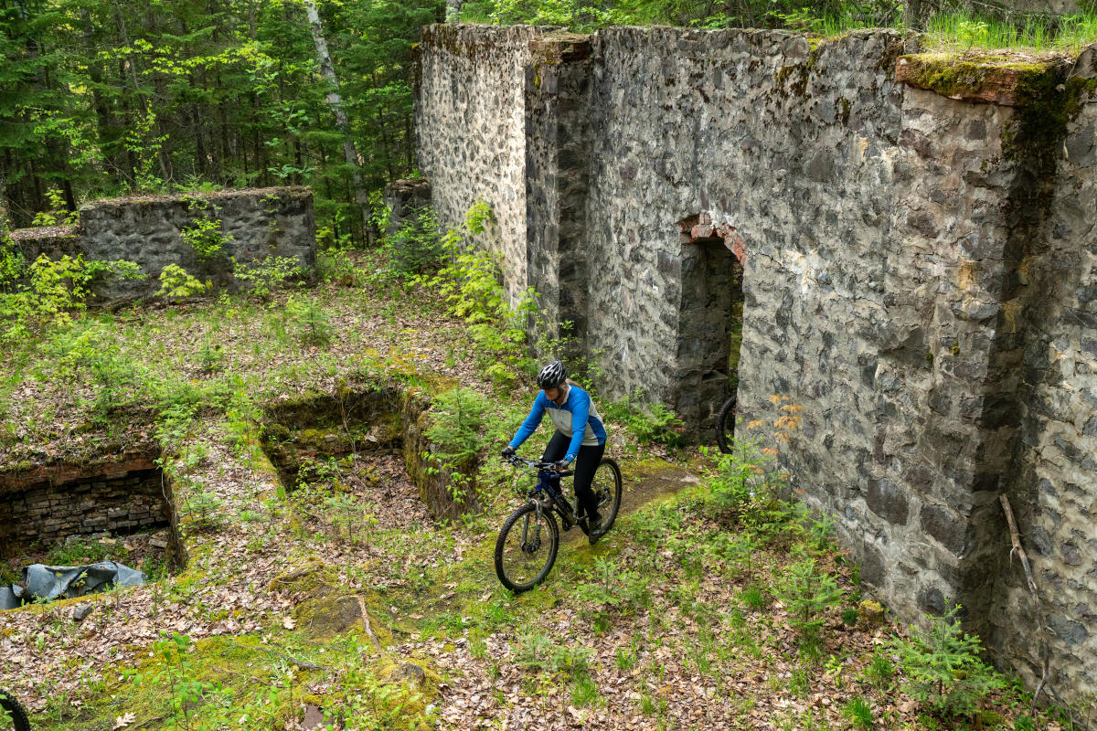 a mountain bike rider weaves through stone building ruins