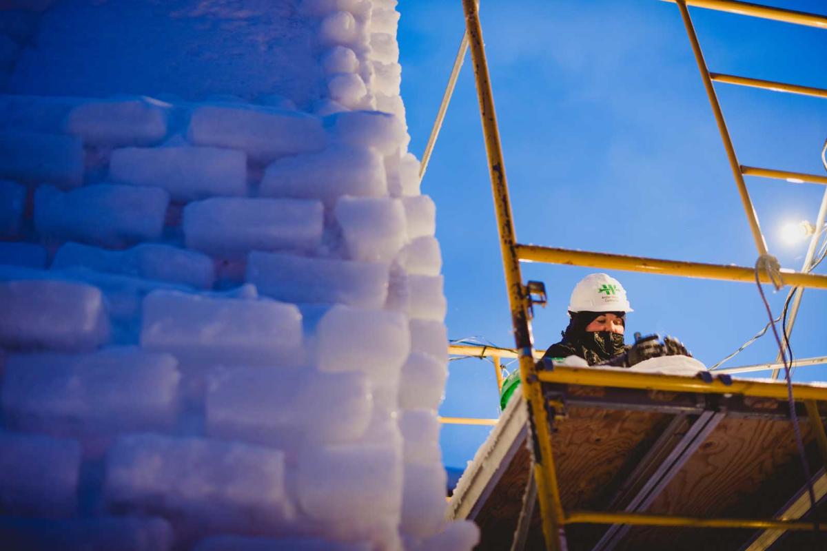 Student on scaffolding works on a snow statue.