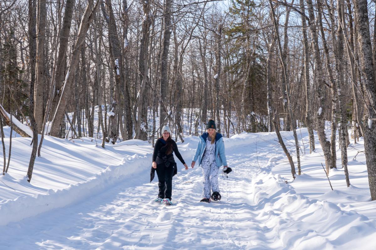 Friends snowshoe along packed snowshoe trail at Mount Bohemia.