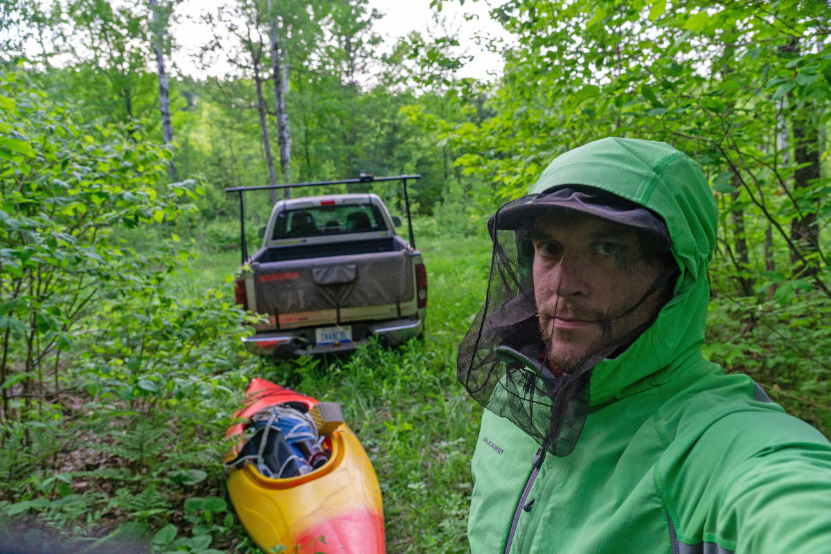 Man wearing  bug nest prepares for a kayaking adventure.