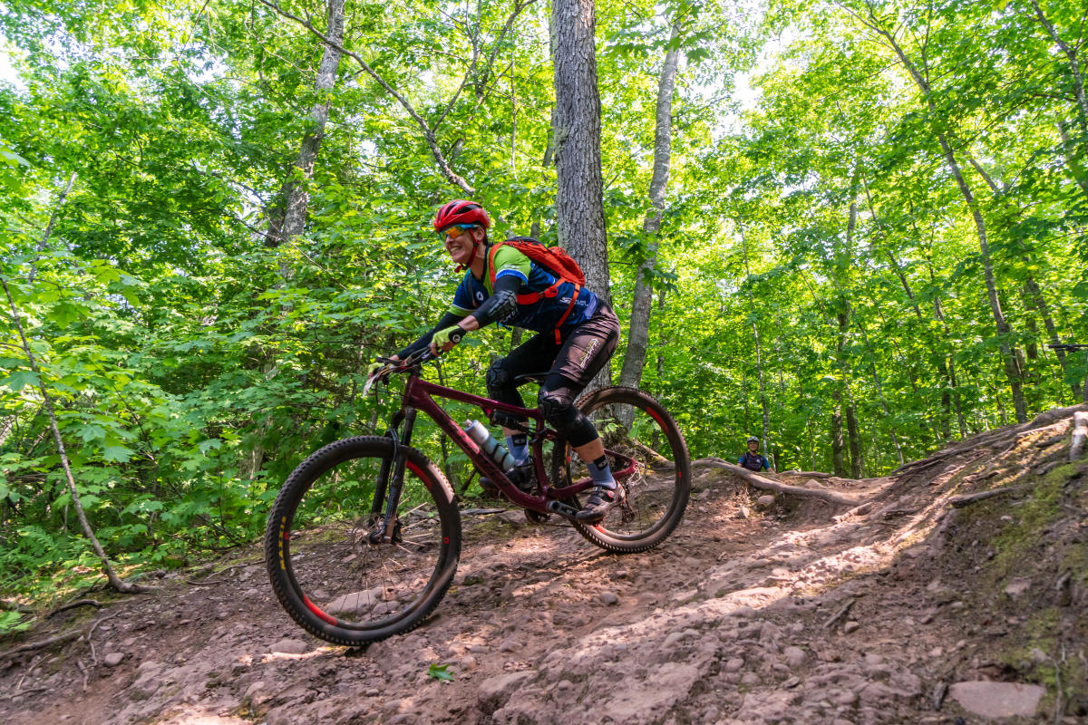 mountain biker rolls down a dirt path through a forest