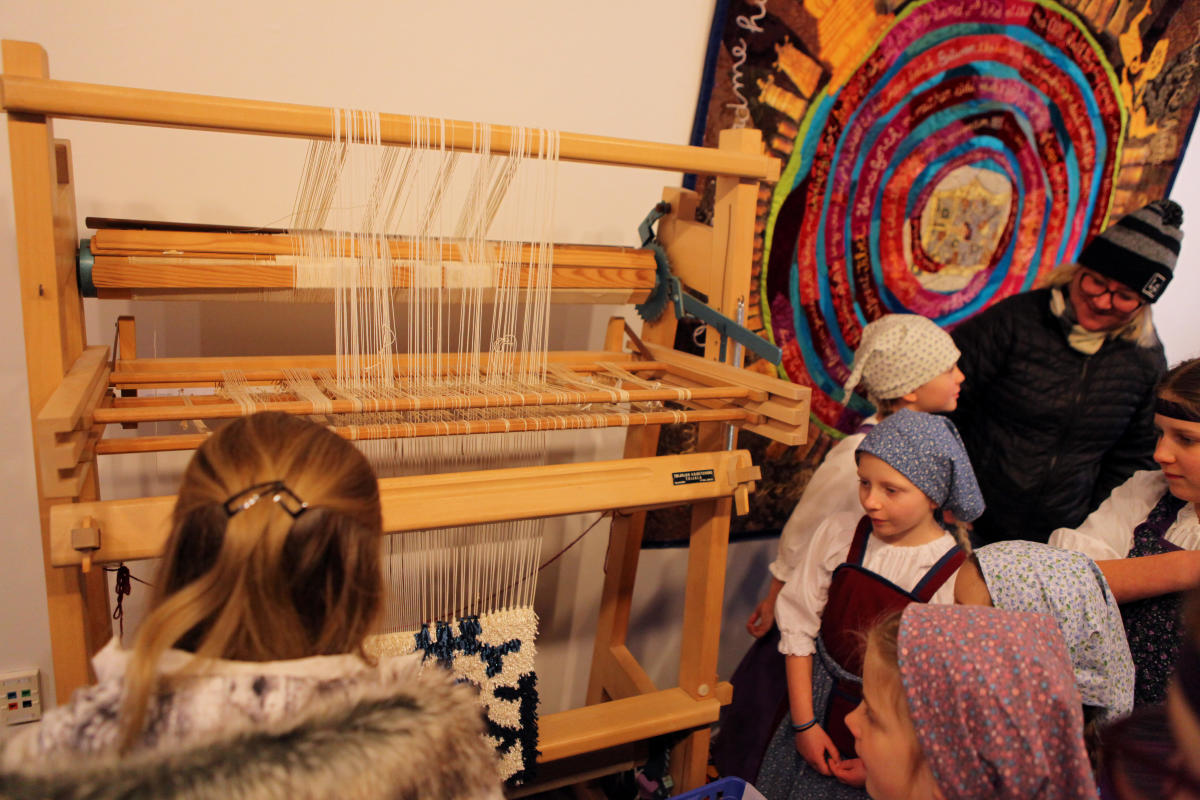 Group observes process of using a loom during Heikinpaiva