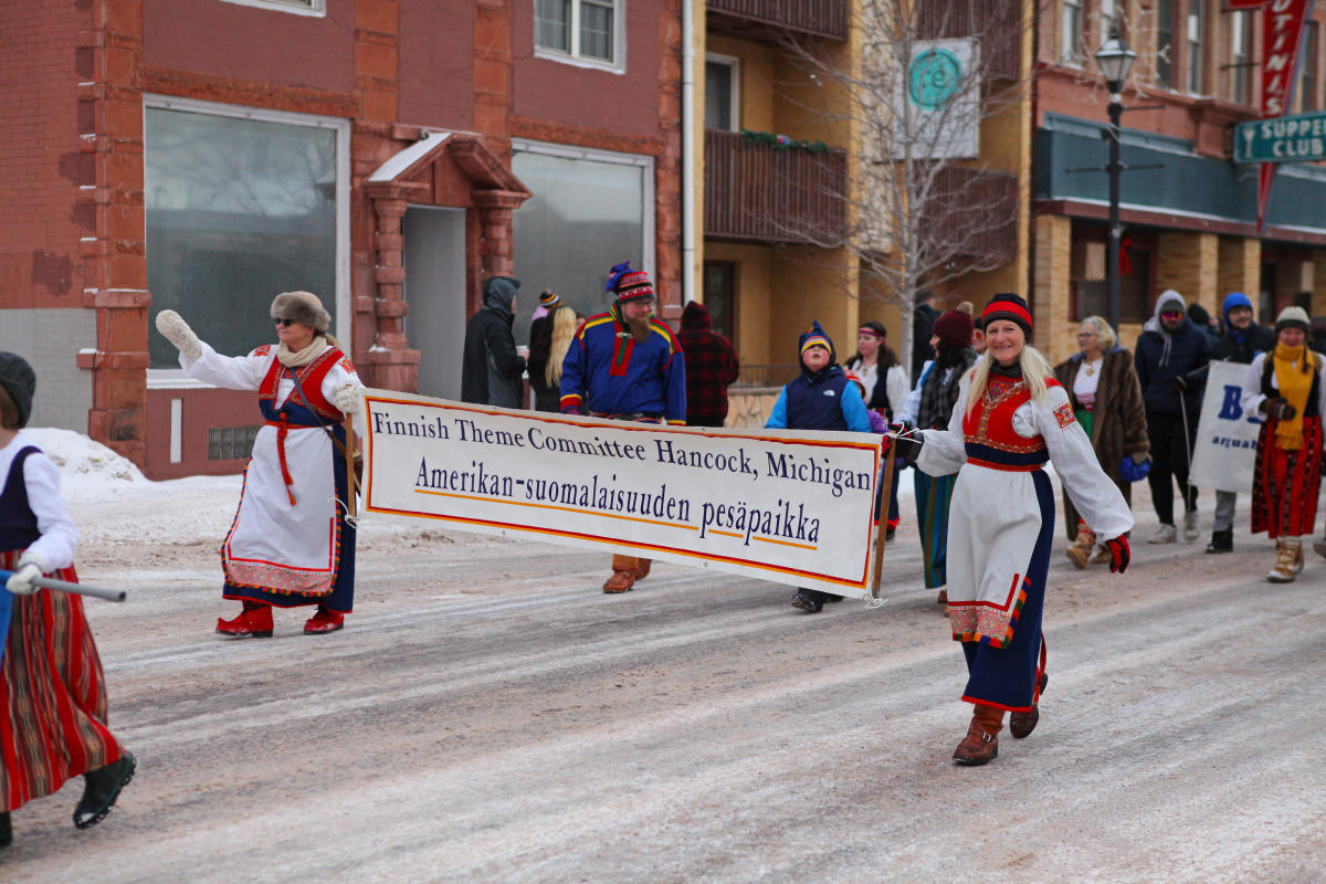 people in traditional finnish costume carry a banner in a parade
