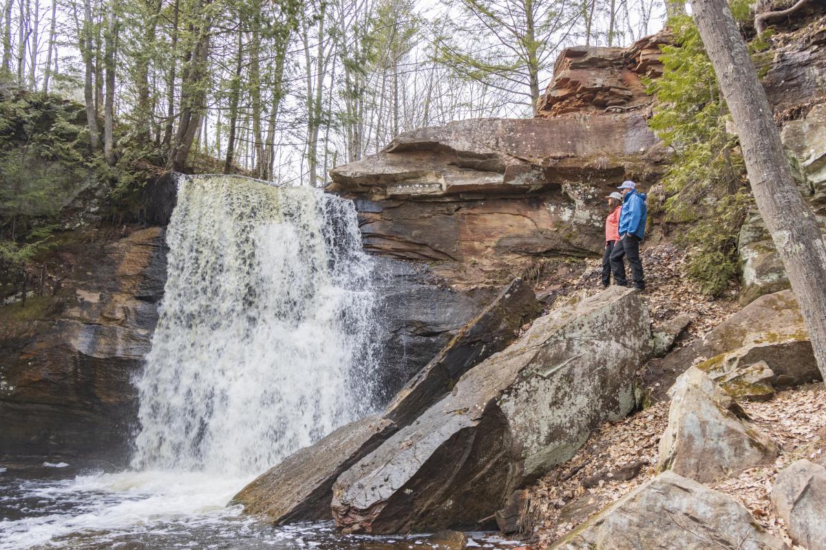 Man and woman stand on rocks overlooking Hungarian Falls in spring.