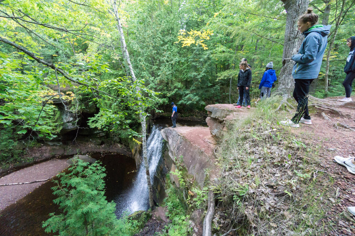 Hikers standing at top of waterfall looking down.