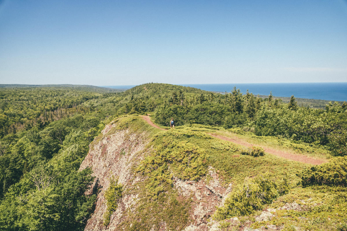 Woman hikes across a ridgeline in the Keweenaw