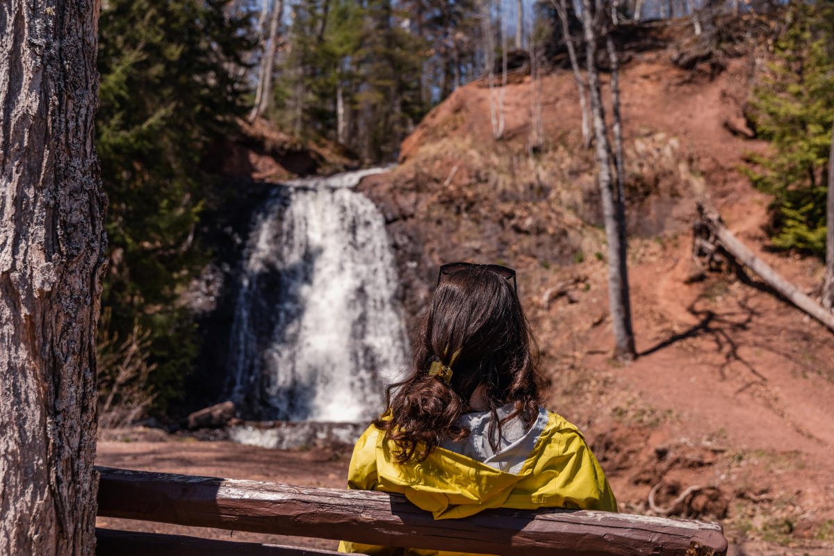 Girl sits on bench looking at Haven Falls