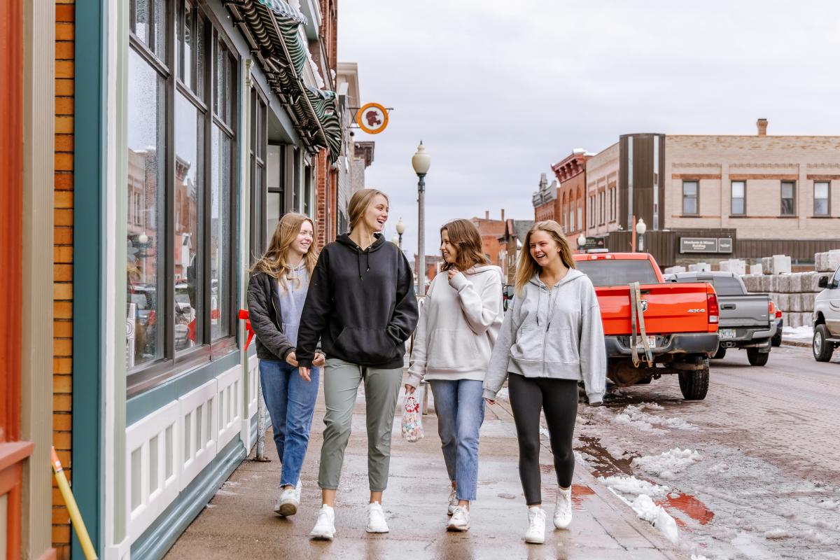 Group of girls walks the sidewalks of downtown Calumet in the art & shopping district.