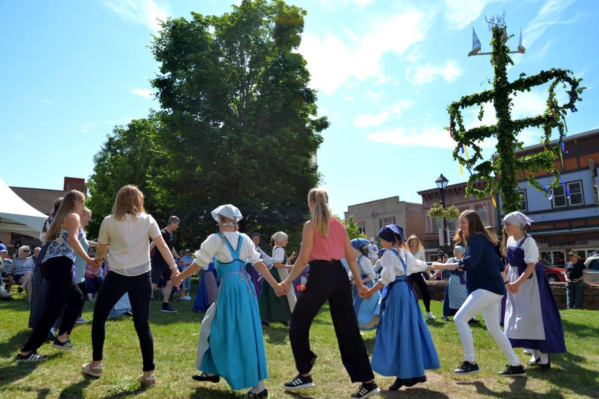 a large group in traditional finnish attire pose with finnish and american flags