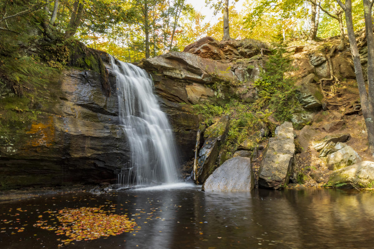 Waterfall during fall with orange leaves pooling in the water
