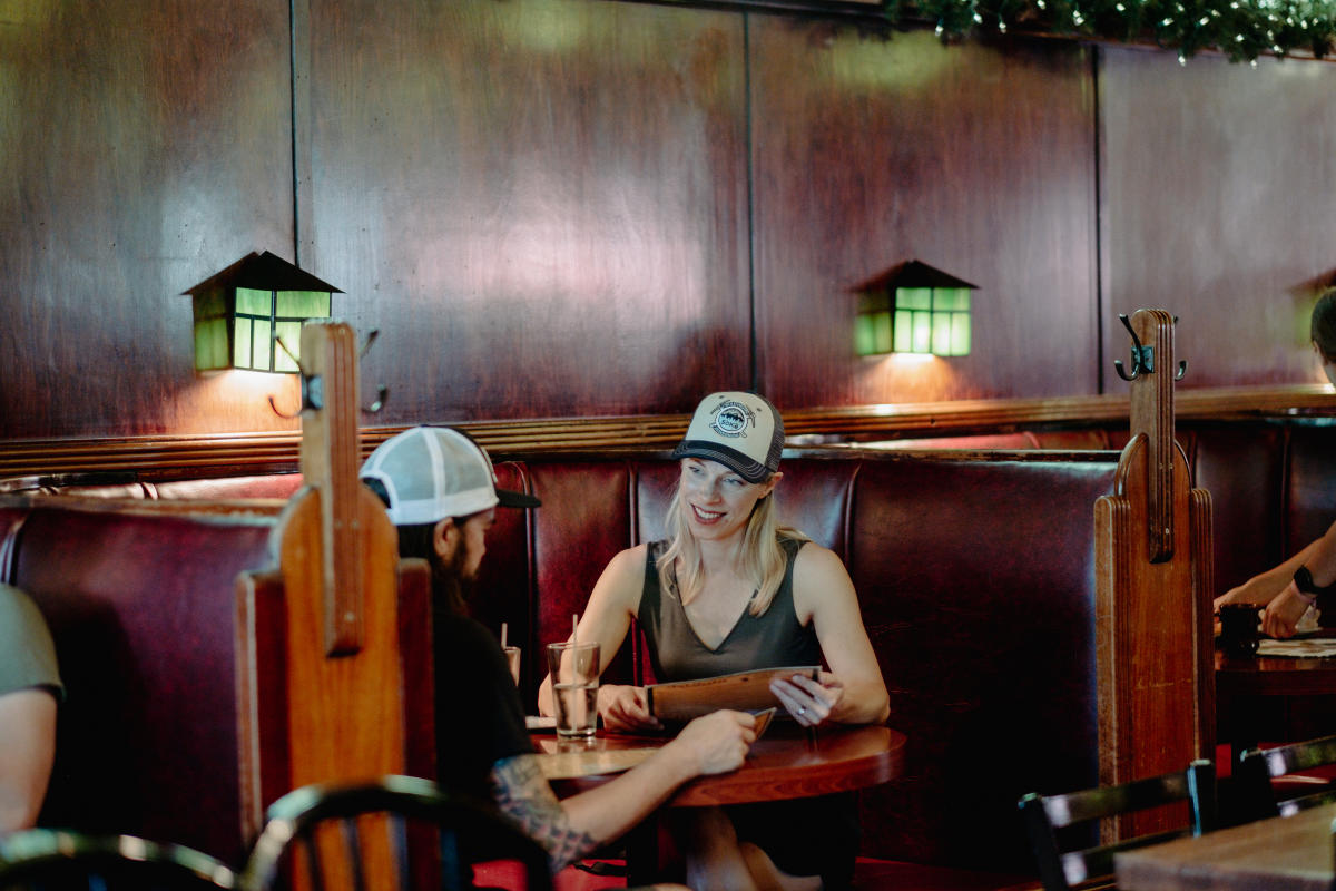 A couple looks at a menu in a booth at a restaurant.