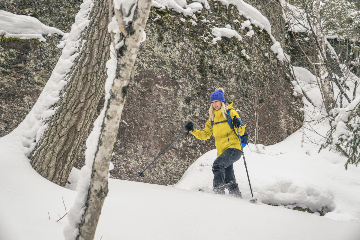 Woman snowshoeing along cliff in deep powder