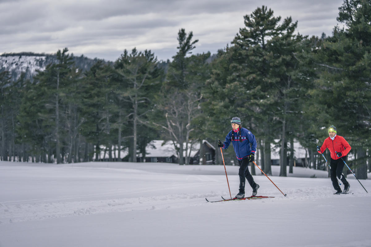 Two classic cross country skiers in front of cabins