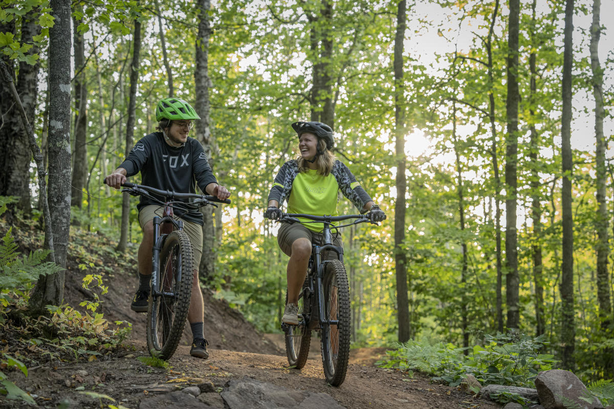 A couple riding mountain bikes in a forest in Copper Harbor