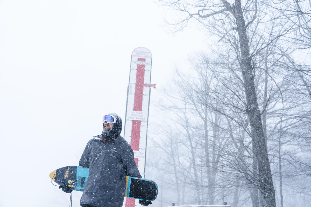 Snowboarder poses for a photo with this snow gauge.