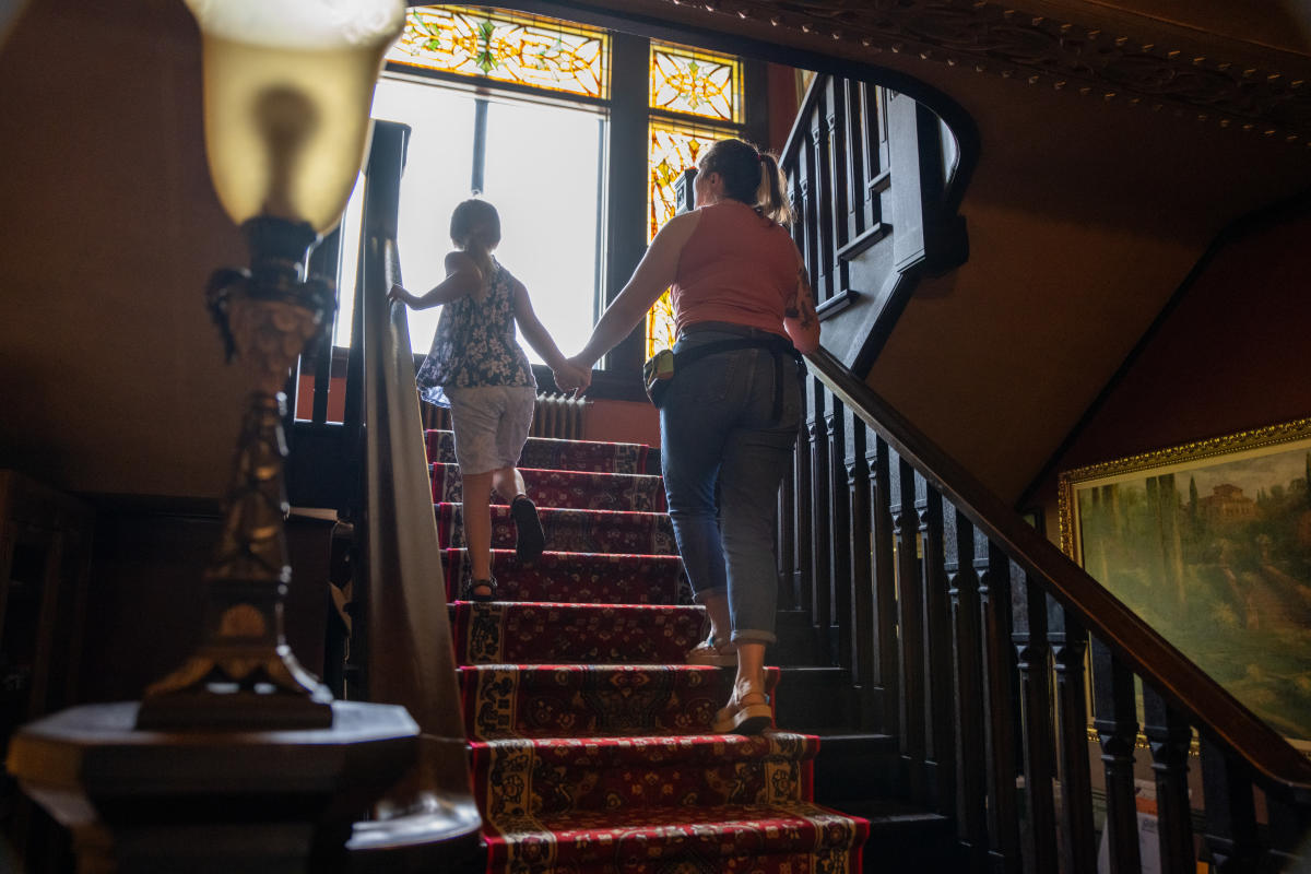 an adult holds a child's hand up a grant staircase