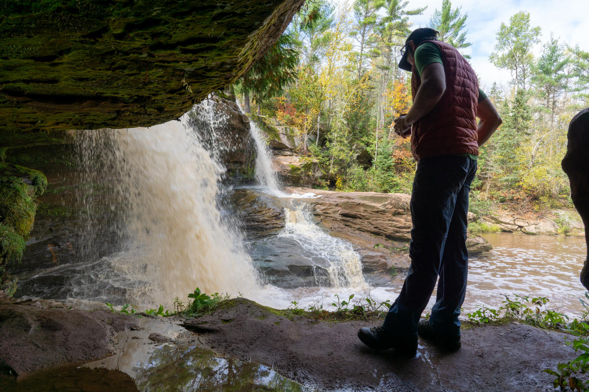 Man stands near rushing waterfall