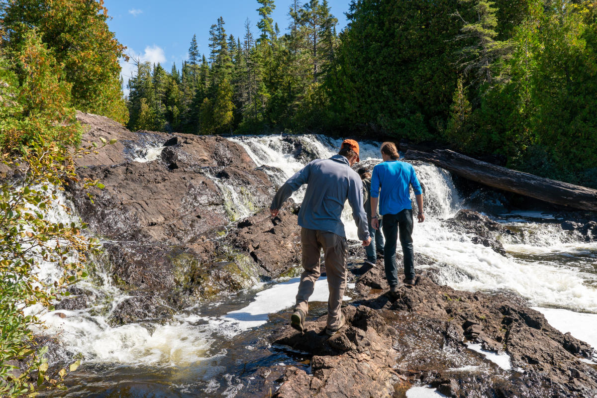 Hikers climb on rocks around Montreal Falls.