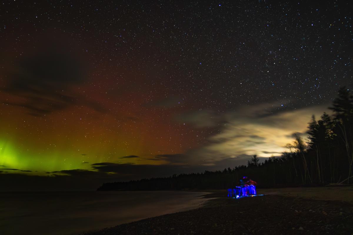 a photo of the aurora features the flashlight of a fellow beachcomber
