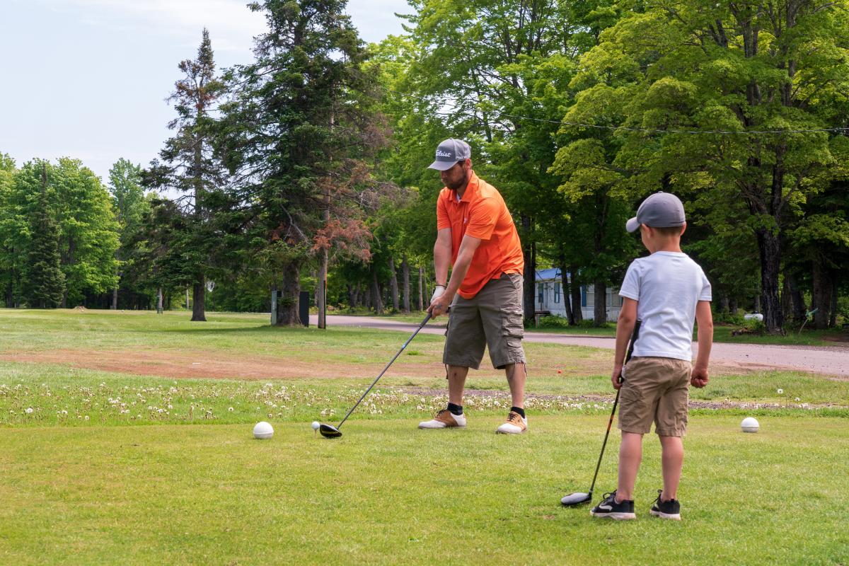 Adult and child play golf at Omer's Golf Course