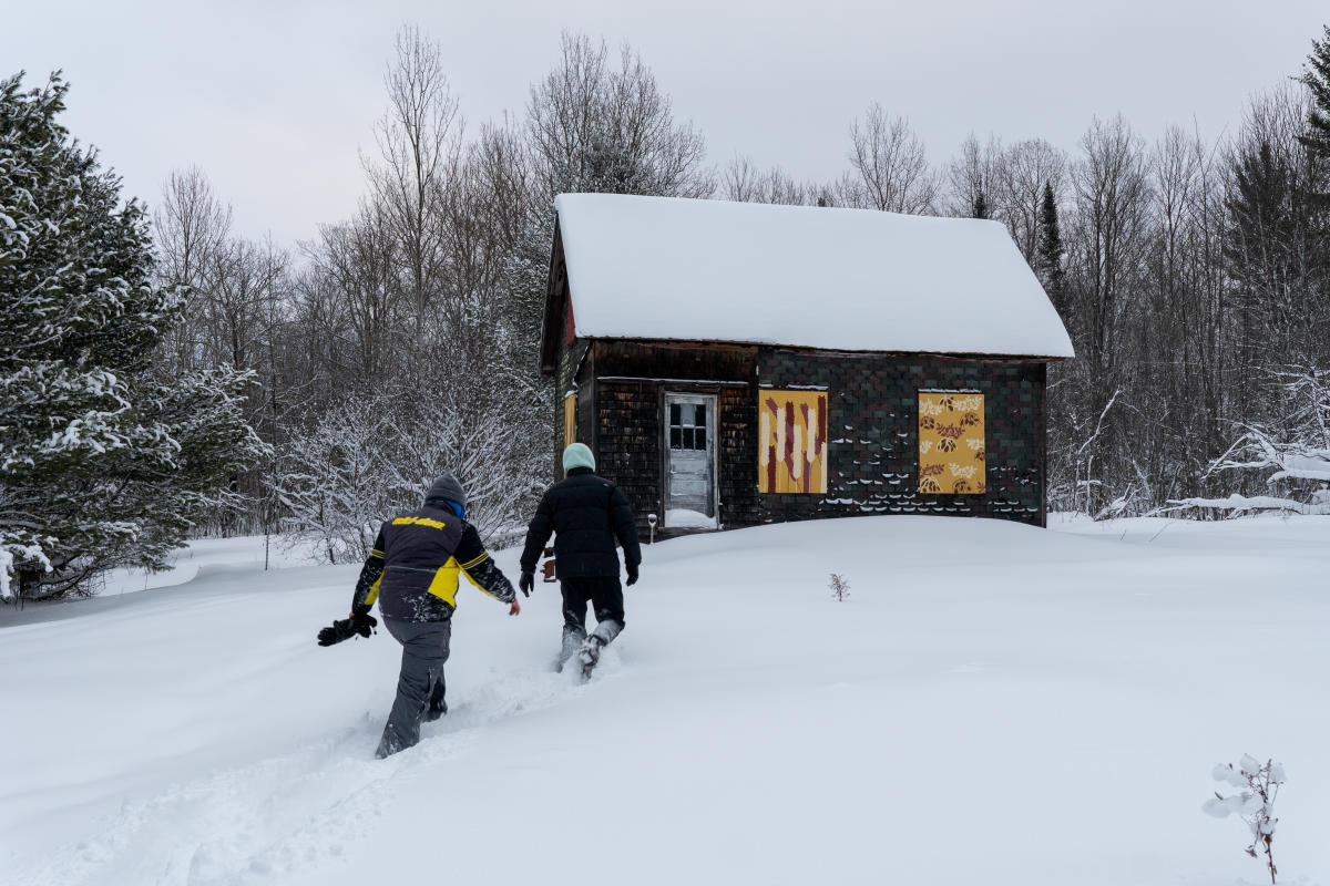 Two snowshoers approach an old farmhouse at Paavola Wetlands.