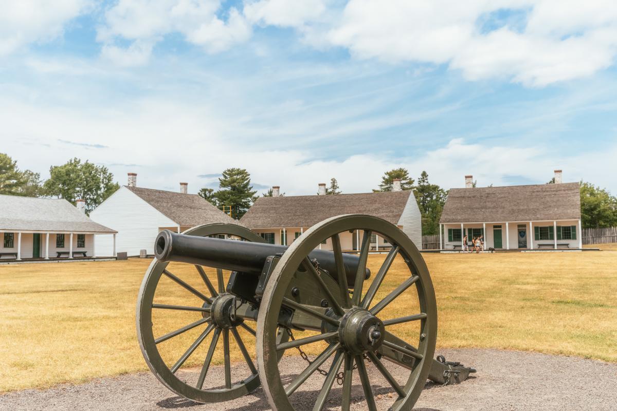 View of cannon in front of historic buildings as Fort Wilkins State Park